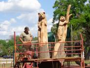 Mark Rice on scaffolding using a chainsaw to carve black bears into wood