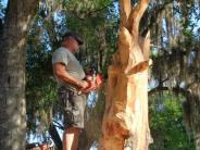 Mark Rice using a chainsaw on a wooden sculpture